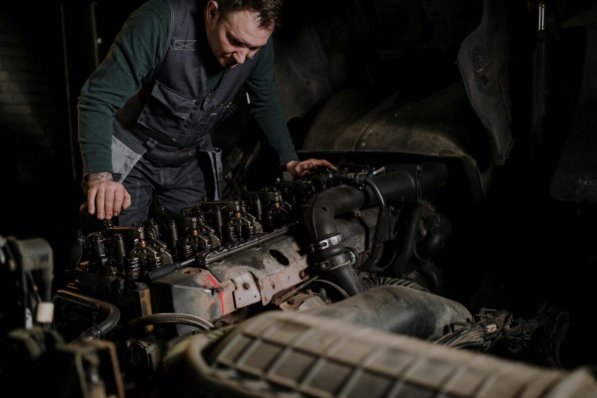 Mechanic leaning over an exposed diesel engine with the valve cover removed